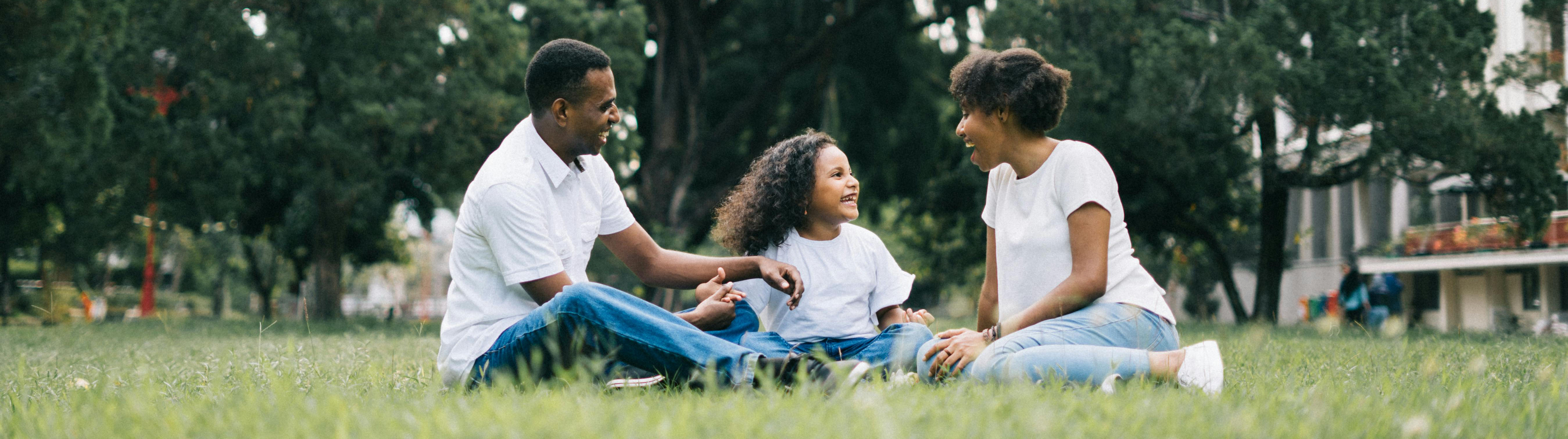 Father, daughter and mother sitting in the grass