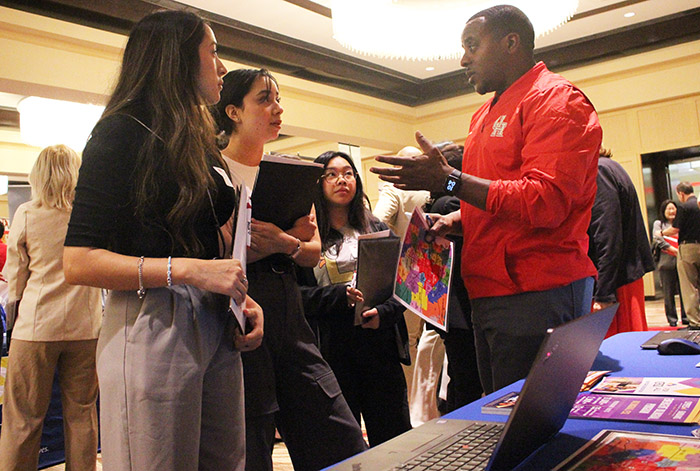 A black male recruiter speaking to three Asian student teachers