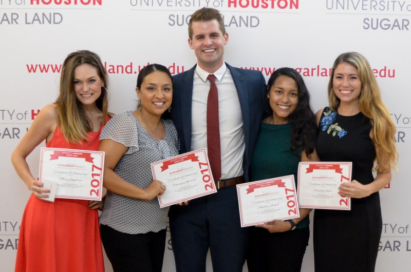 Students holding up scholarship certificate