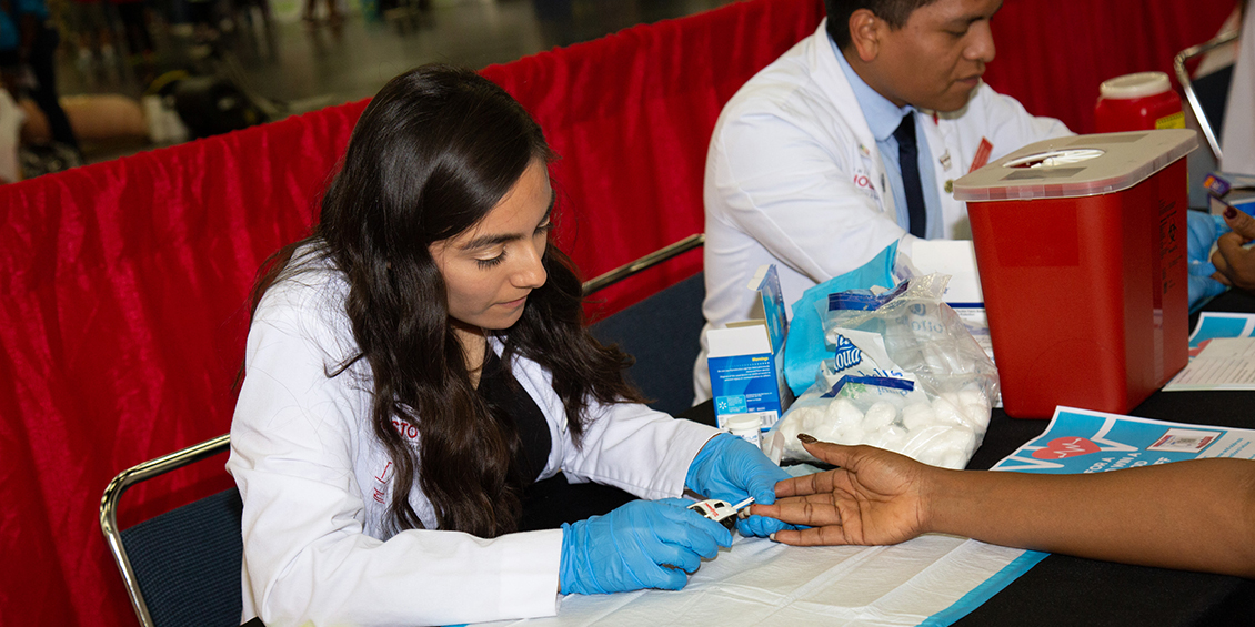 Students measures blood sugar of patient.