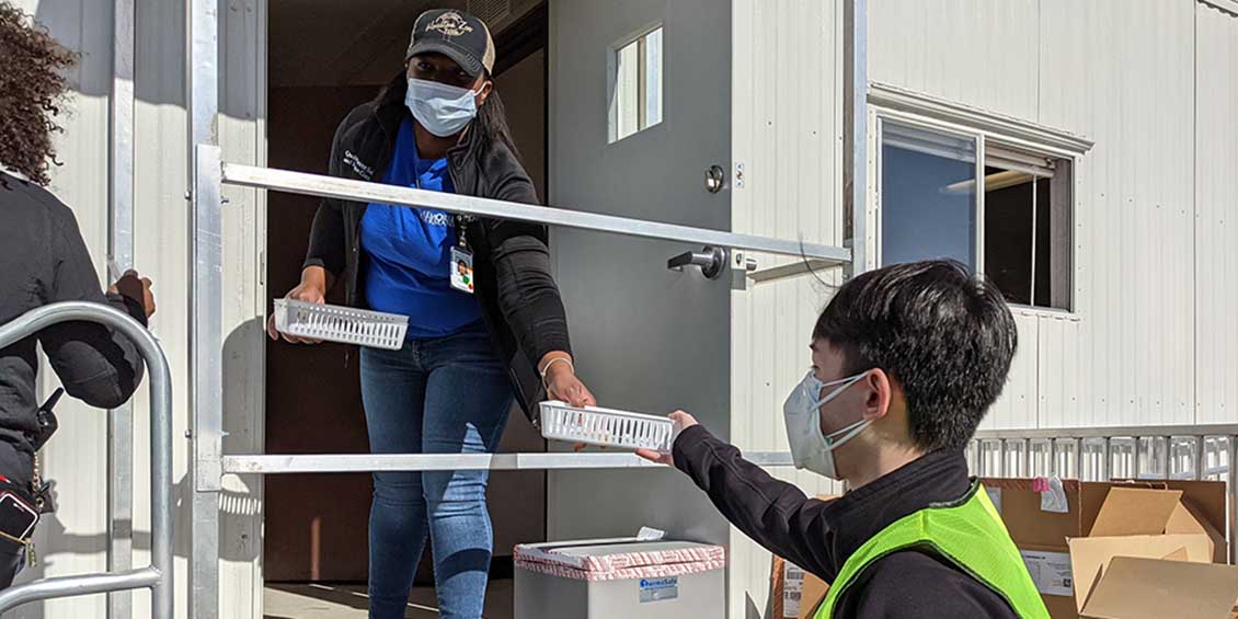 student transports covid vaccine tray