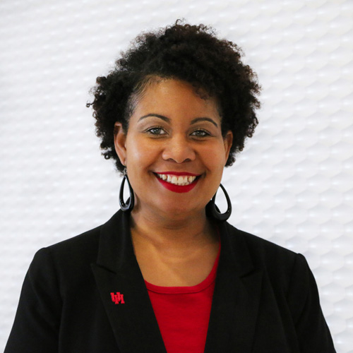 Portrait of a black woman smiling with dark ear length hair wearing a black suit